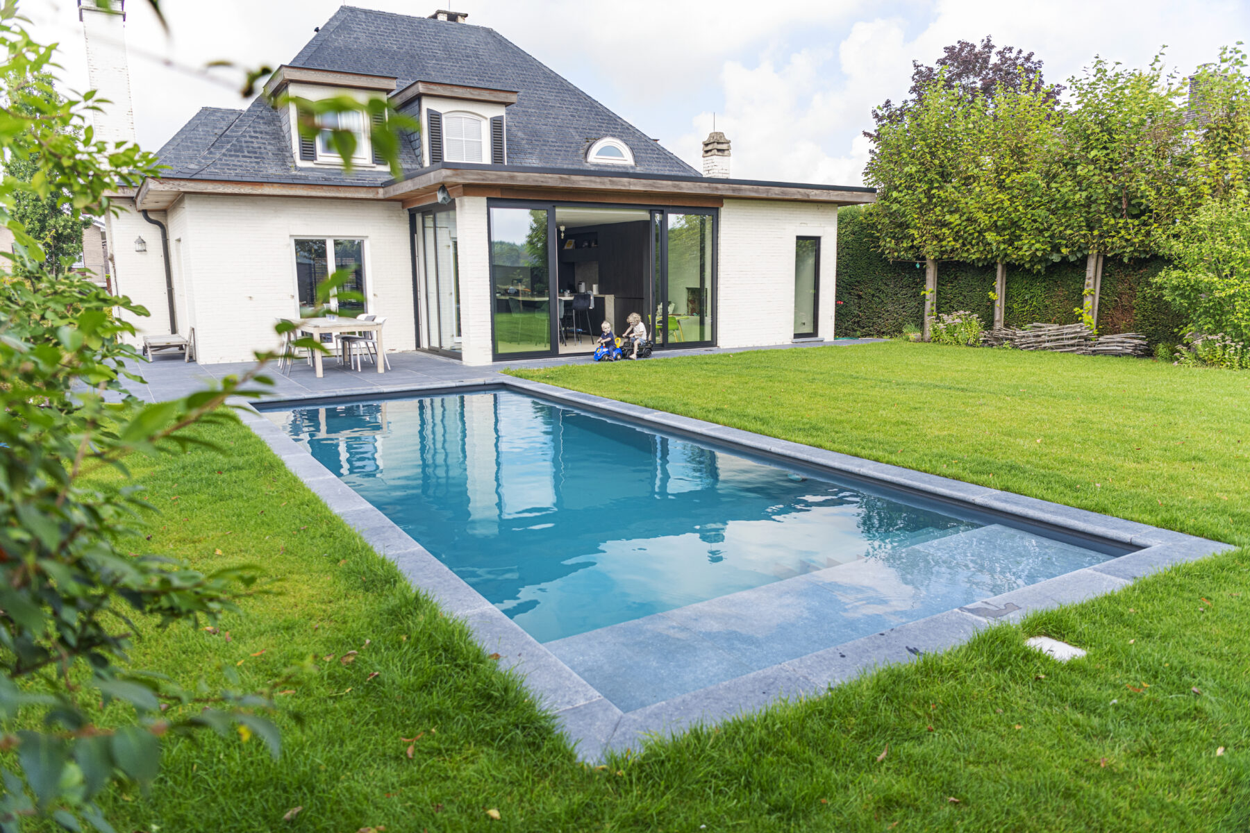 zelf een zwembad bouwen project Steenokkerzeel afgewerkt zwembad en zicht op huis
